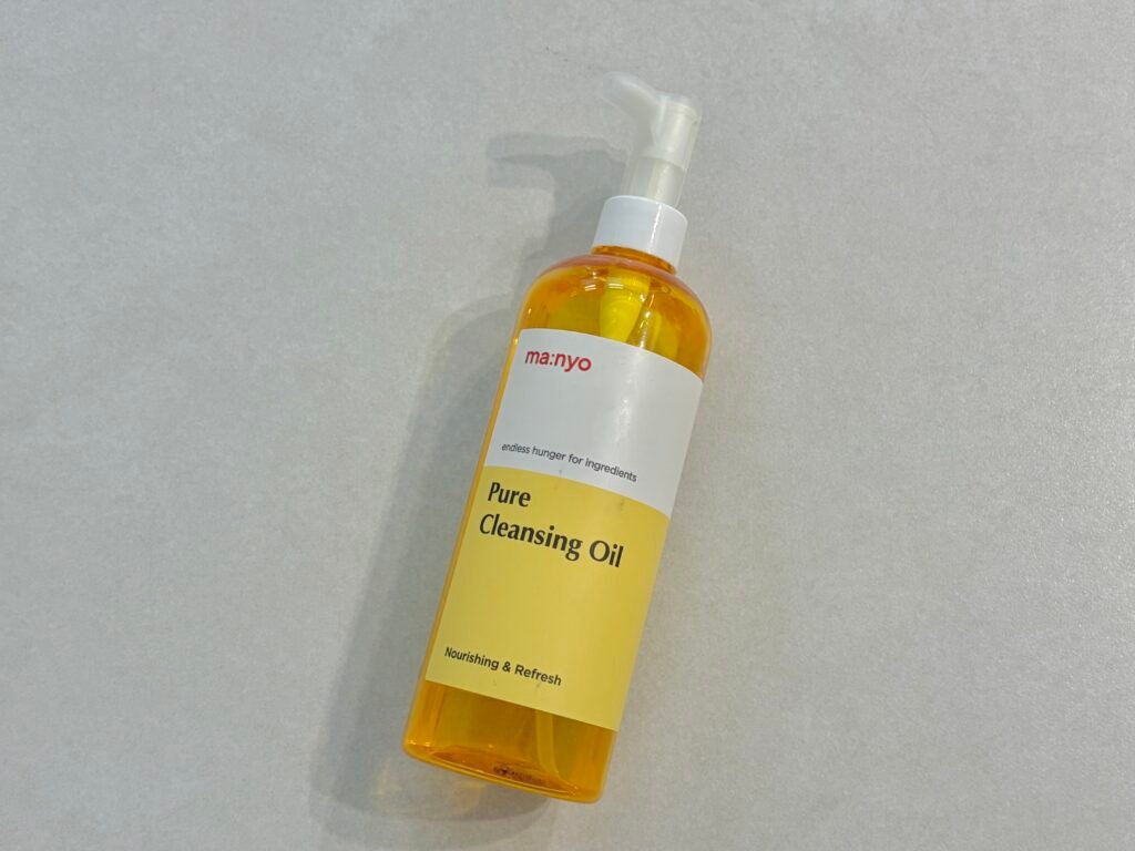 Manyo Factory Pure Cleansing Oil golden bottle displayed on a bathroom counter for Korean double cleansing review.
