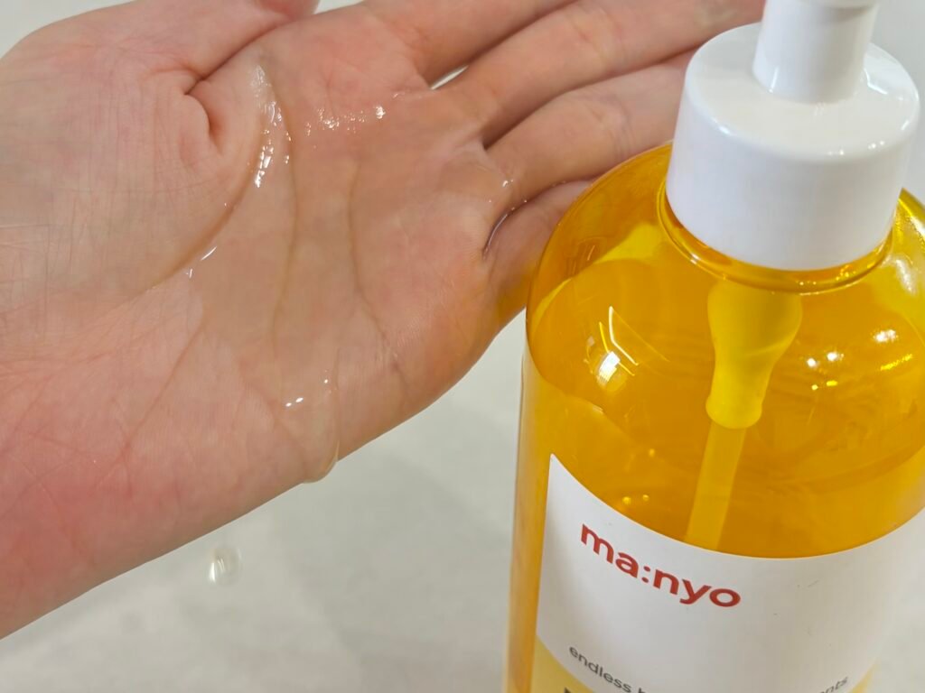 Lightweight and runny texture of Manyo Pure Cleansing Oil dropping onto a palm for gentle double cleansing.