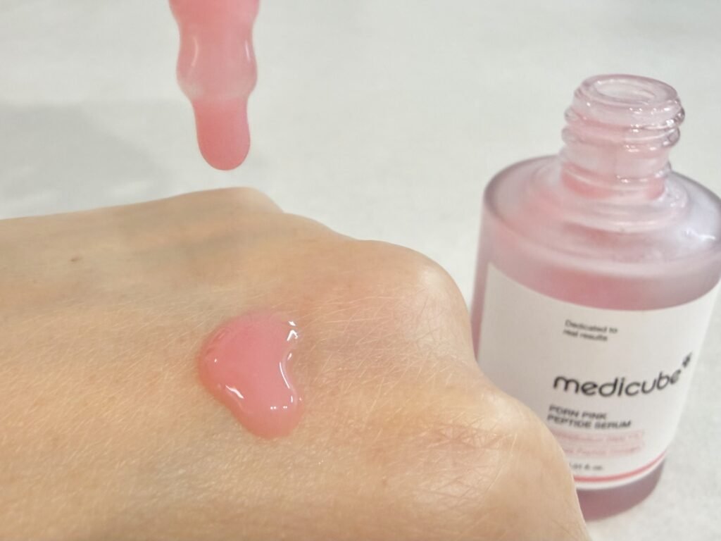 Dropping pink viscous Medicube PDRN ampoule directly onto the back of the hand