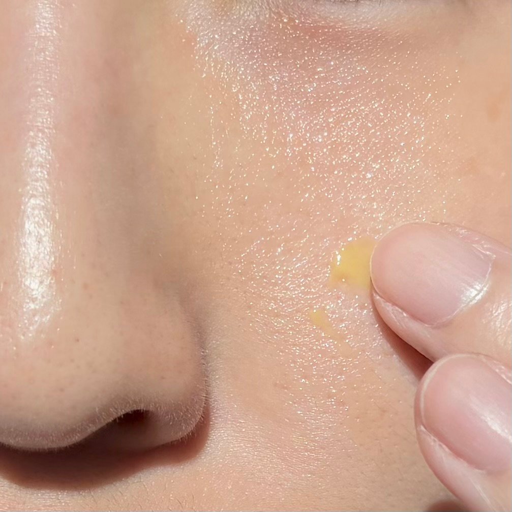 Applying lightweight yellow retinal booster cream onto cheek and pore area for targeted firming