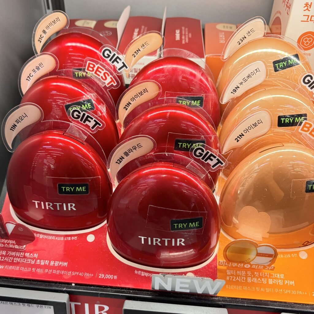TIRTIR Mask Fit Red Cushion compacts displayed alongside orange aura cushions at an Olive Young store in Seoul