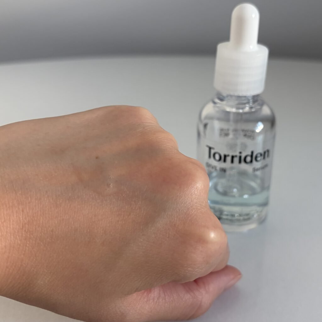 Torriden Dive-In Low Molecule Hyaluronic Acid Serum bottle with a clear, lightweight hydration droplet swatched on hand.